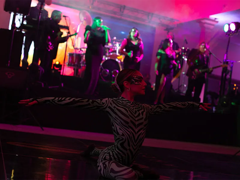 Bailarina con banda completa en escenario con luces